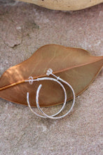 Load image into Gallery viewer, Silver hoop earrings on a textured surface with a leaf