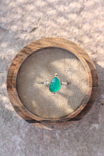 Load image into Gallery viewer, bright green stone in a gold ring in a wooden box on a stone background