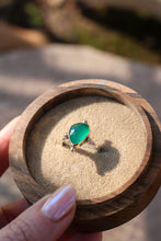 Load image into Gallery viewer, bright green stone in a gold ring in a wooden box on a stone background