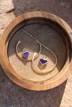 Load image into Gallery viewer, Gold hoop earrings with heart-shaped purple opal stones in a wooden box.