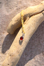 Load image into Gallery viewer, Gold bracelet with a red garnet gemstone on a textured stone surface