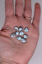 Load image into Gallery viewer, Hand holding several turquoise stones against a neutral background
