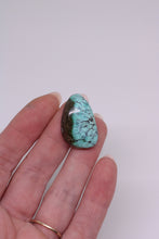 Load image into Gallery viewer, Turquoise stone held in a hand against a white background
