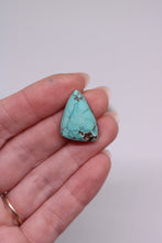 Load image into Gallery viewer, Turquoise stone held in a hand against a plain background
