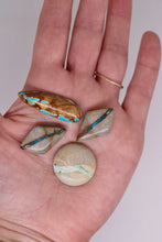 Load image into Gallery viewer, Hand holding four turquoise stones on a plain background
