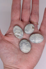 Load image into Gallery viewer, Hand holding four oval-shaped stones with a plain background
