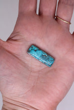 Load image into Gallery viewer, Turquoise stone held in a hand against a neutral background
