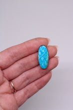 Load image into Gallery viewer, Turquoise stone held in a hand against a plain background
