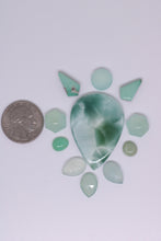 Load image into Gallery viewer, Collection of green stones with a quarter for scale on a white background
