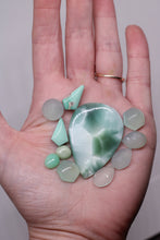 Load image into Gallery viewer, Hand holding a collection of green and white stones against a neutral background

