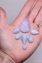 Load image into Gallery viewer, Hand holding light blue-purple teardrop-shaped stones against a neutral background

