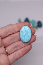 Load image into Gallery viewer, Hand holding a large turquoise stone against a blurred background
