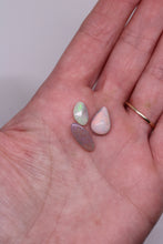 Load image into Gallery viewer, Three small opal stones held in a hand against a neutral background

