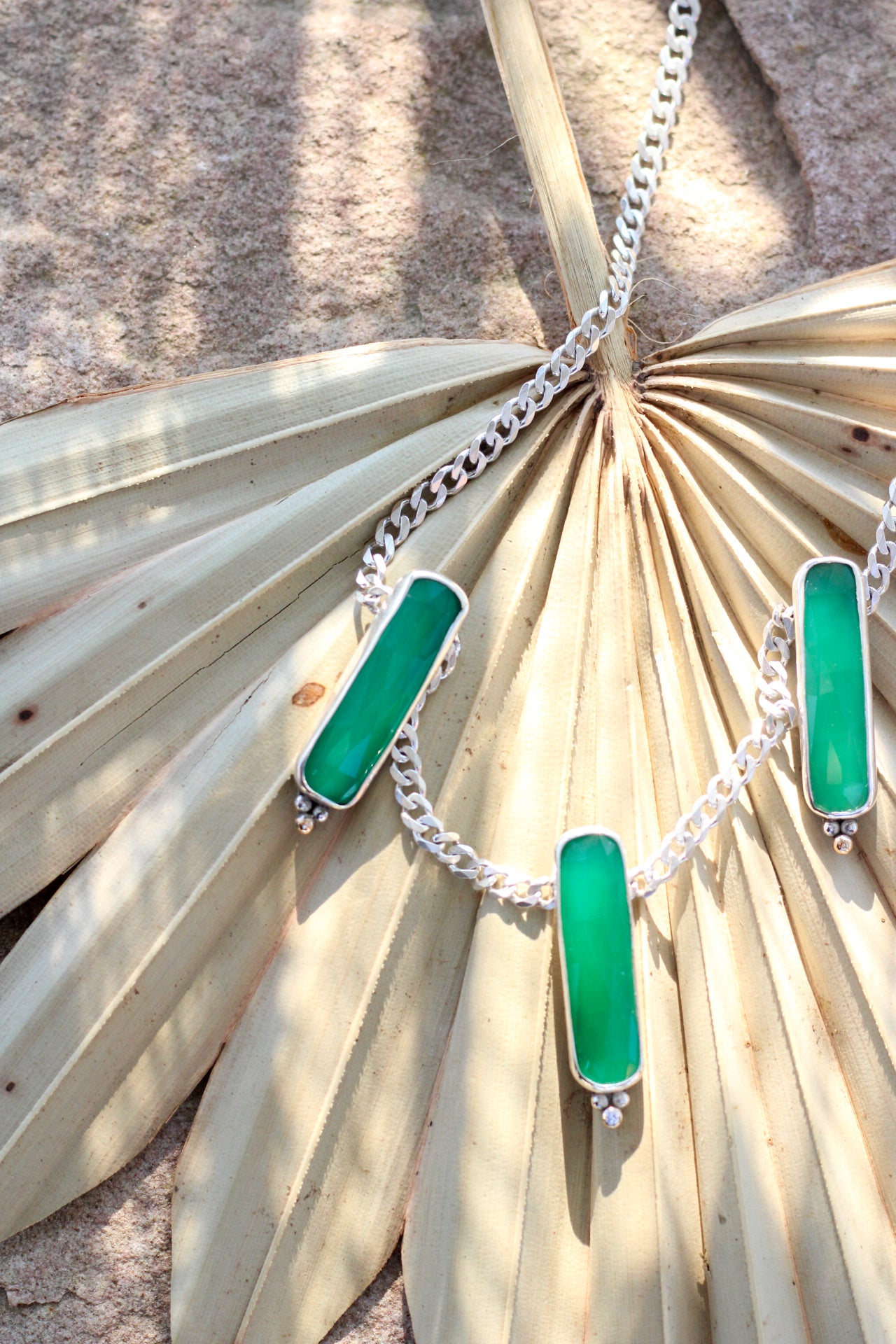 Necklace with green pendant on a palm leaf