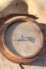 Load image into Gallery viewer, Silver ring with a vintage component  design next to two baguette diamonds in a wooden box on a stone surface
