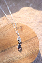 Load image into Gallery viewer, Silver necklace with a purple gemstone pendant on a wooden surface

