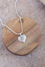 Load image into Gallery viewer, Silver heart-shaped pendant necklace on a wooden coaster
