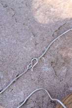 Load image into Gallery viewer, Silver snake chain necklace clasp on a textured stone surface

