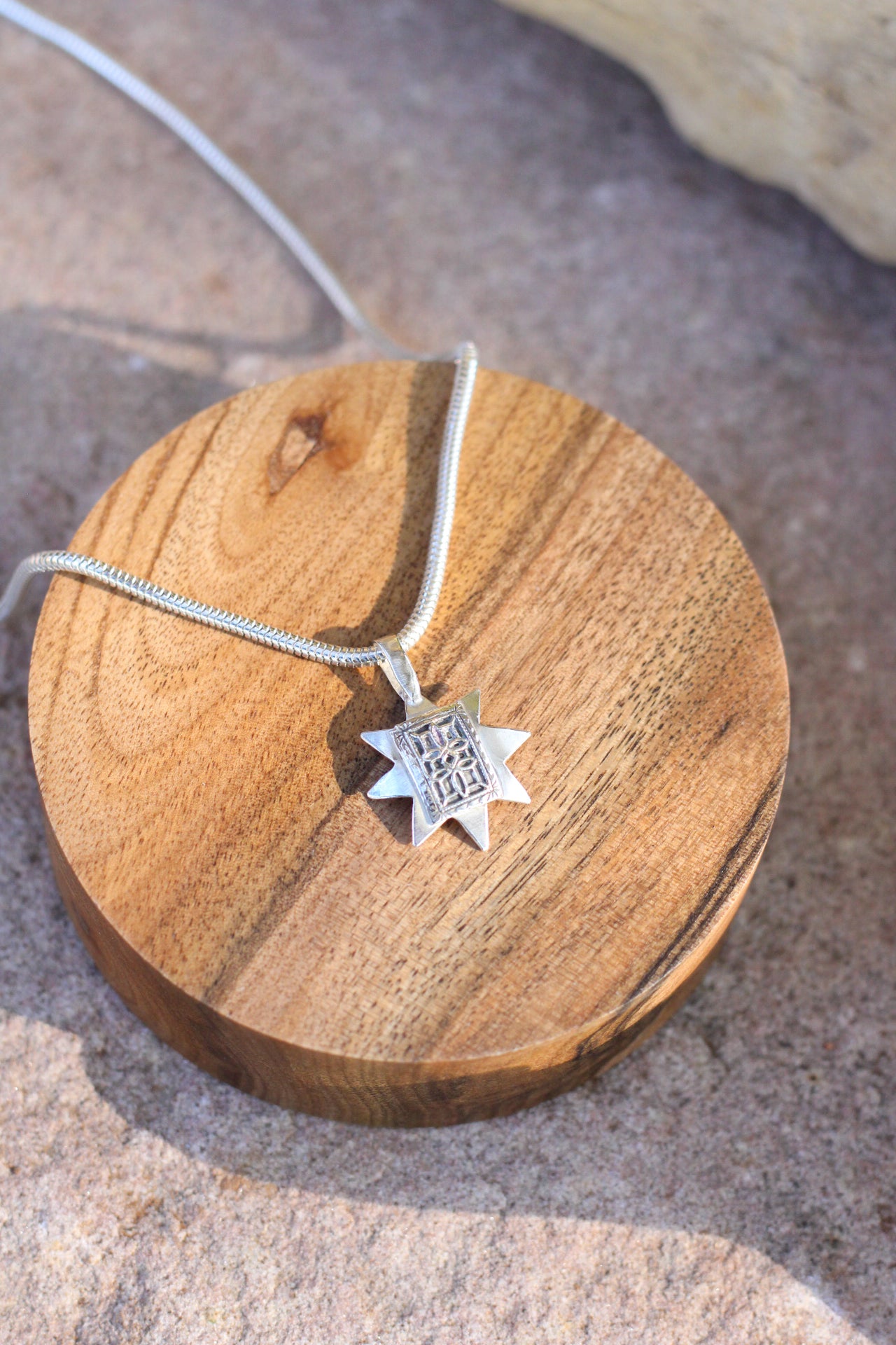 Silver necklace with a star-shaped pendant on a wooden block