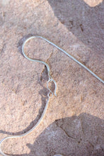 Load image into Gallery viewer, Silver snake chain necklace clasp on a textured stone surface
