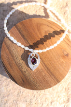 Load image into Gallery viewer, Necklace with a pearl chain, red gemstone pendant, and silver vintage heart lock charm on a wooden surface.

