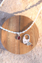 Load image into Gallery viewer, Necklace with a pearl chain, red gemstone pendant, and silver vintage heart lock charm on a wooden surface.
