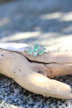 Load image into Gallery viewer, Ring with a blue-green gemstone on a piece of driftwood by a body of water
