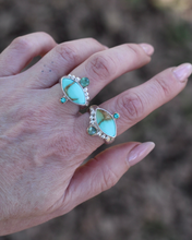 Load image into Gallery viewer, Turquoise colored rings with emerald accents on a hand against a blurred natural background
